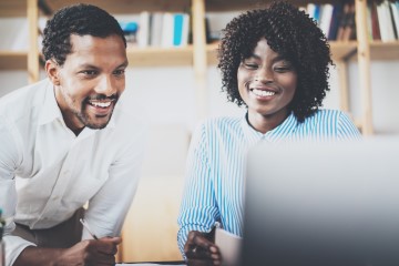 2 african american professionals looking at a laptop